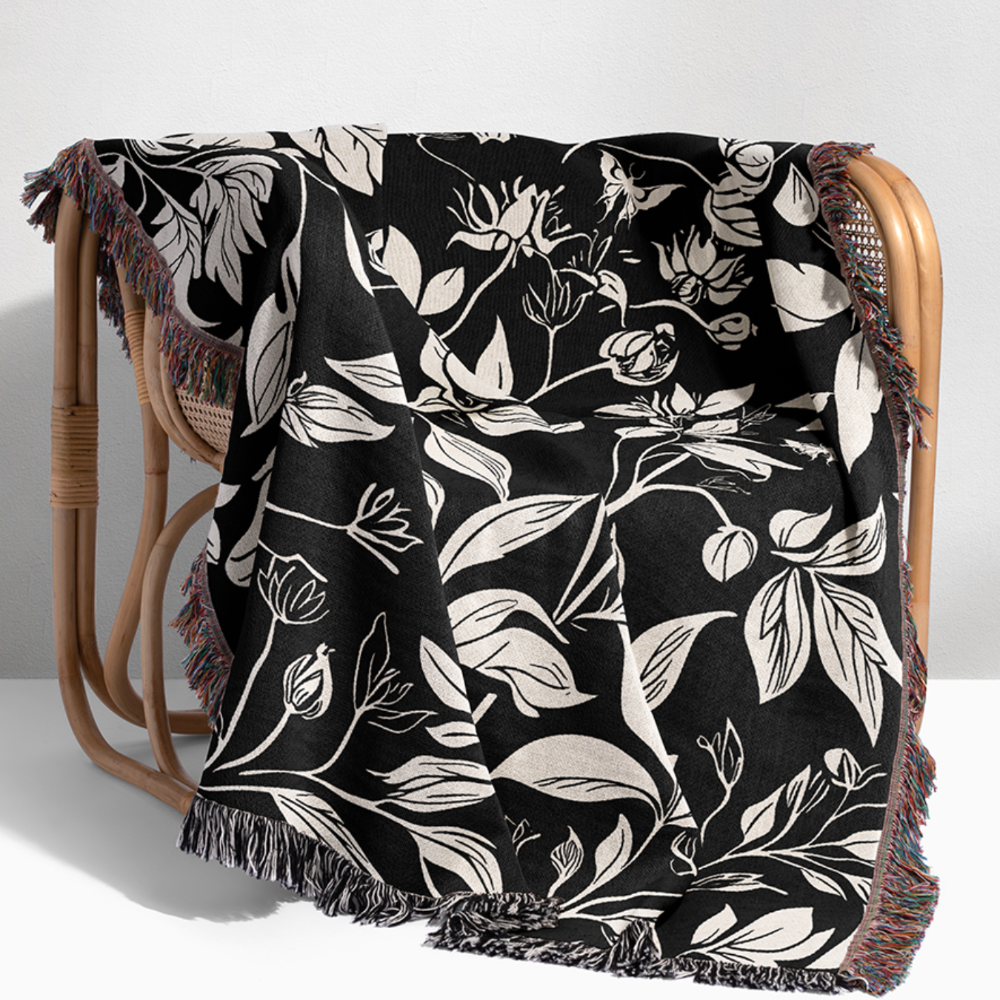 Black and white woven floral design woven blanket in black in white layed out on the chair